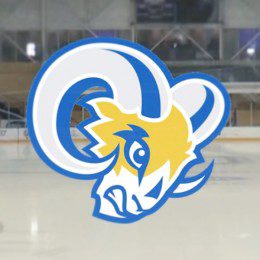 A ram head, that's yellow, blue, grey and white in colour. There is an ice rink in the background.